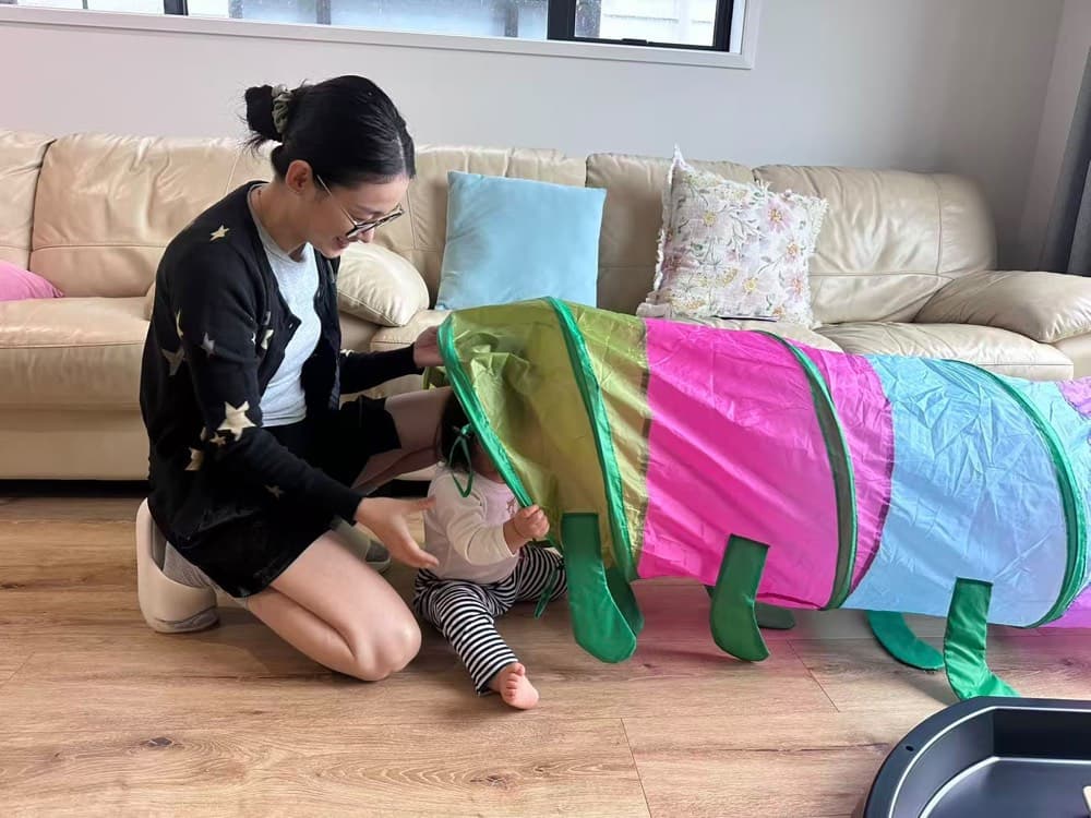 Caregiver and toddler playing with a colourful tunnel