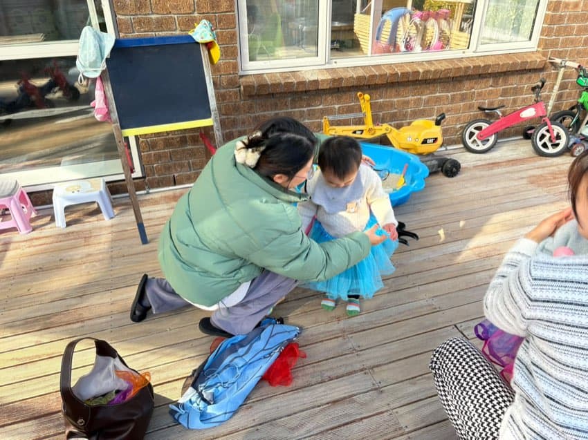 Caregiver supporting a toddler during outdoor play