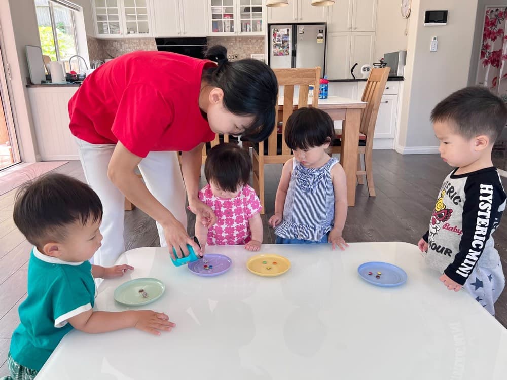 Caregiver leading a group learning activity with young children
