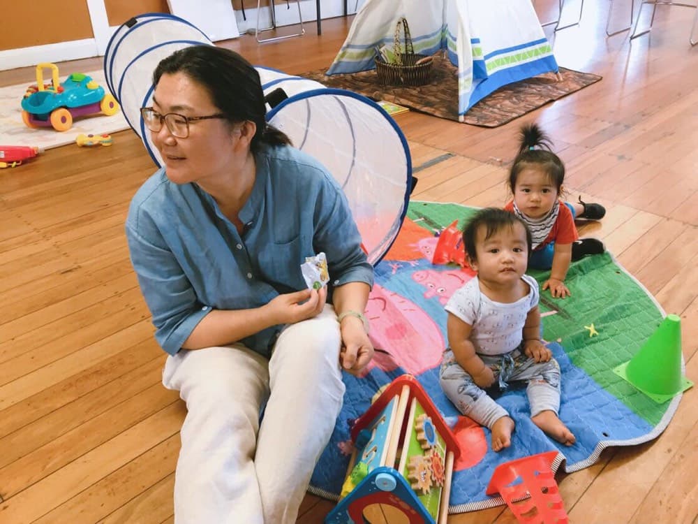 Caregiver with infants during indoor playtime