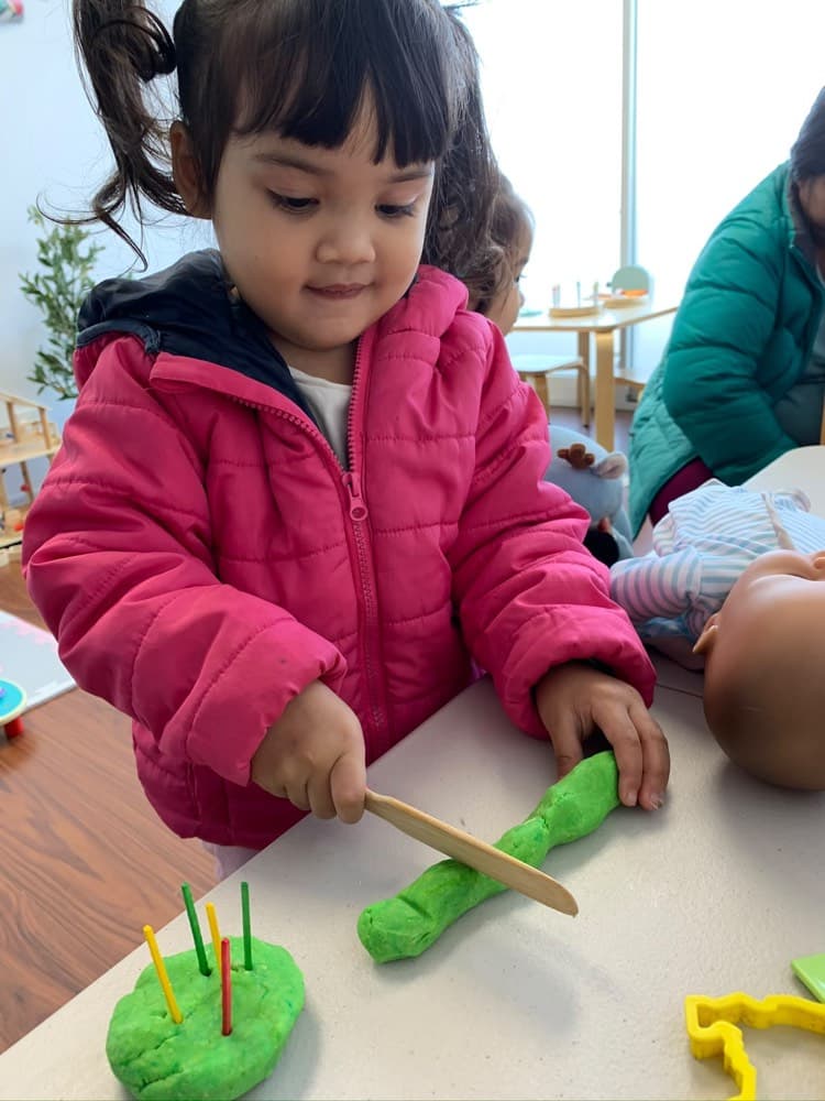 Child creating shapes with green play dough
